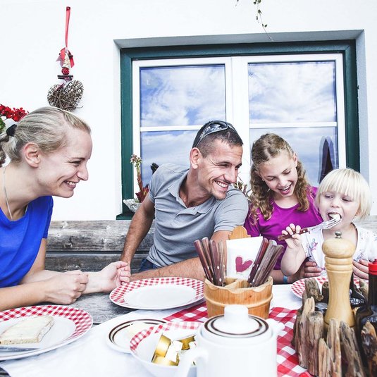 Familienzeit im Interalpen-Hotel Tyrol ©Region Seefeld, Stephan Elsler Eine Familie beim gemeinsamen Abendessen im Außenbereich der Almhütte