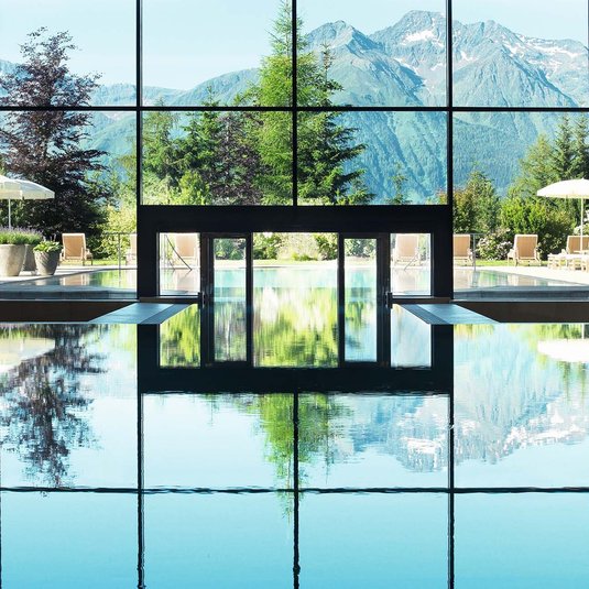 Pool mit Blick auf die Tiroler Bergwelt Aufnahme des Indoorpools im lichtdurchfluteten Spa-Bereich mit einzigartigem Blick auf die umliegende Bergwelt