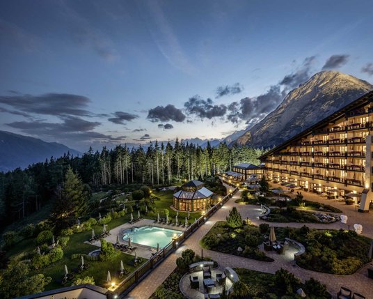Außenansicht des beleuchteten Interalpen Leading Hotels in Tirol in einer lauen Sommernacht
